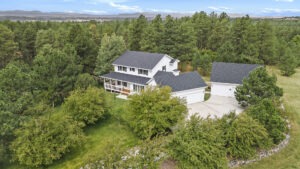 High-quality aerial drone image of a luxury two-story home surrounded by abundant trees on a 2-acre property.