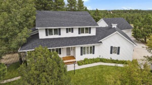 High-quality aerial drone image of a luxury two-story home showcasing the front of the property with views of the surrounding area behind the home.