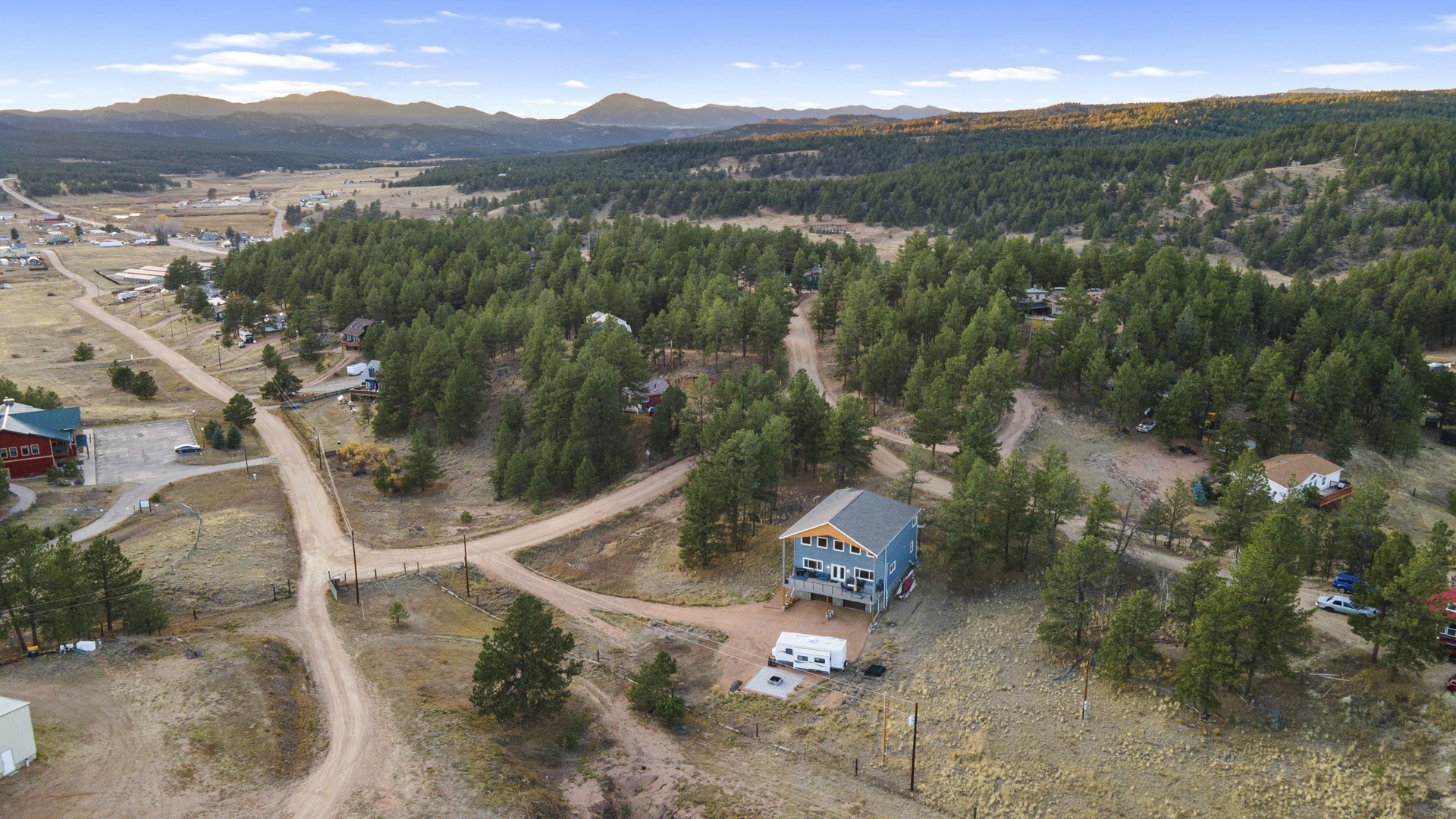 High aerial drone photo of a newly built two-story mountain home in Colorado, showcasing the 1-acre lot and the surrounding area with mountain views.