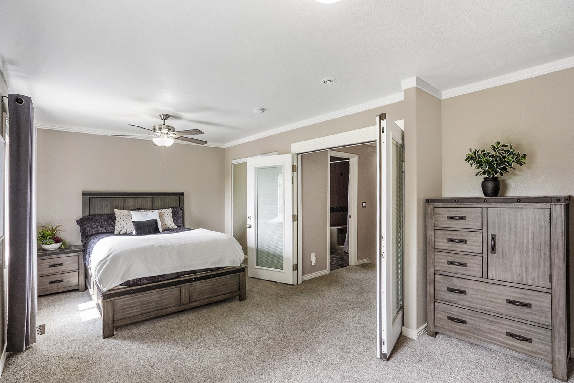 Modern primary bedroom with carpet, French doors, and a ceiling fan.