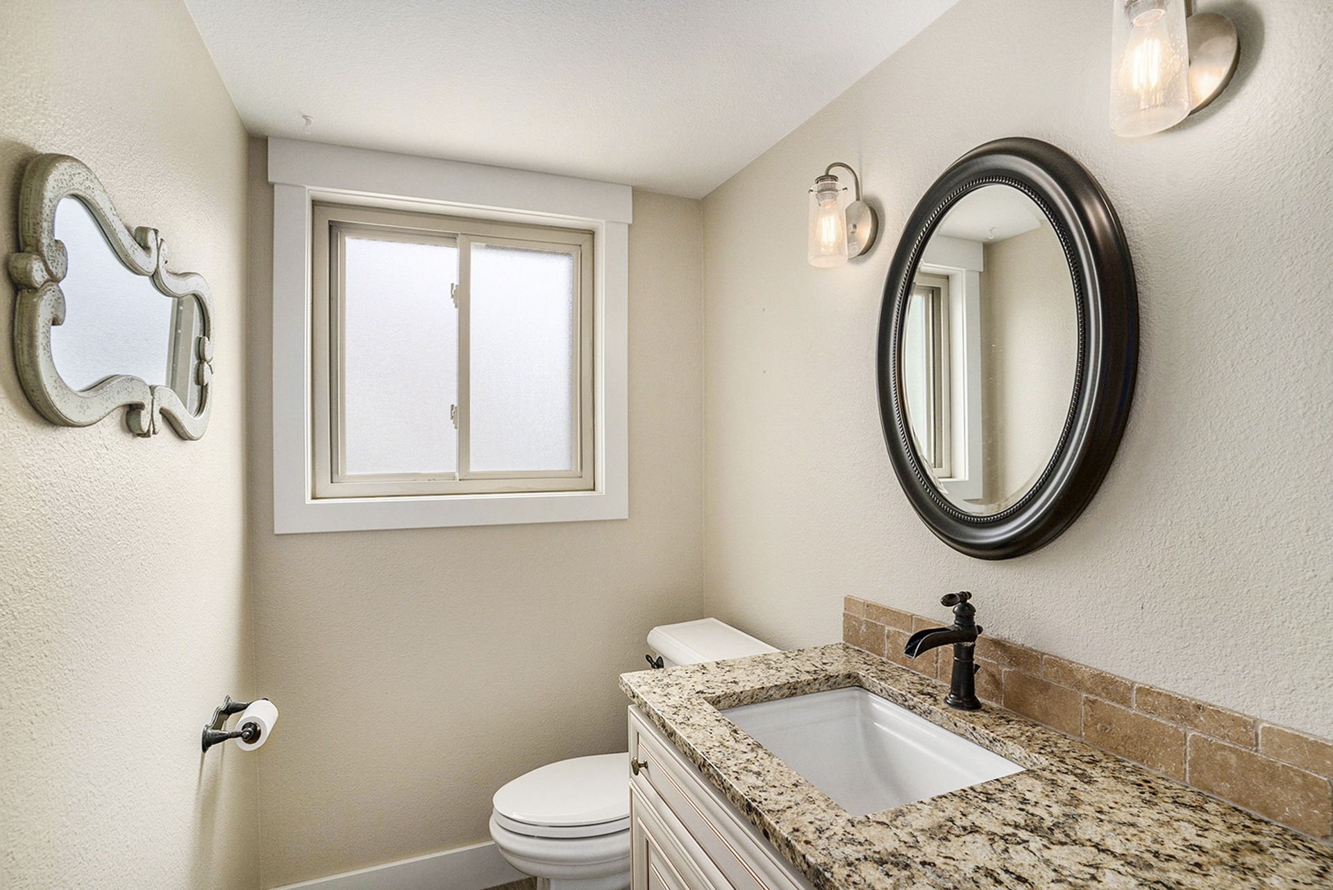 Warm secondary half bathroom with a vanity, mirror, modern lighting, toilet, and a window.