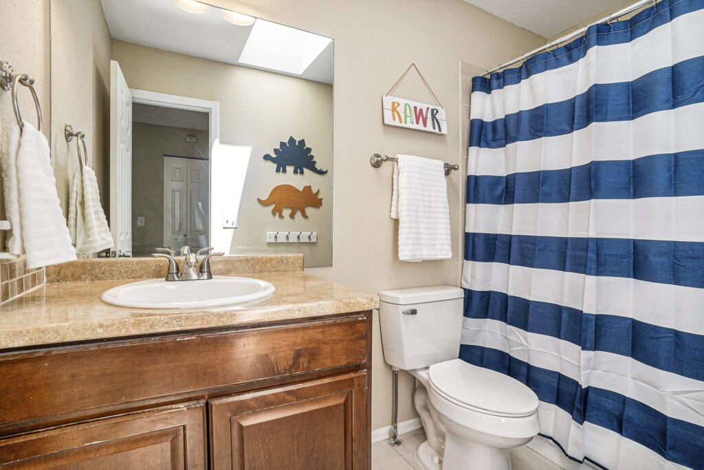 Bathroom with a skylight, vanity, and shower/tub combination.