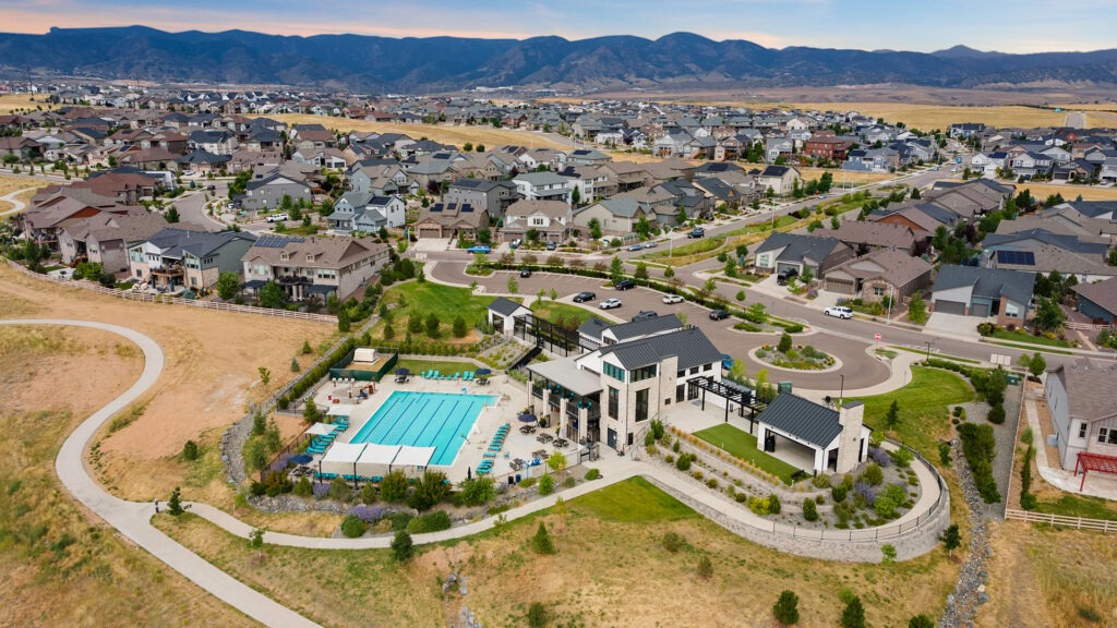 Aerial drone photo of a Denver neighborhood with community pool, trail system, and Rocky Mountains in the background