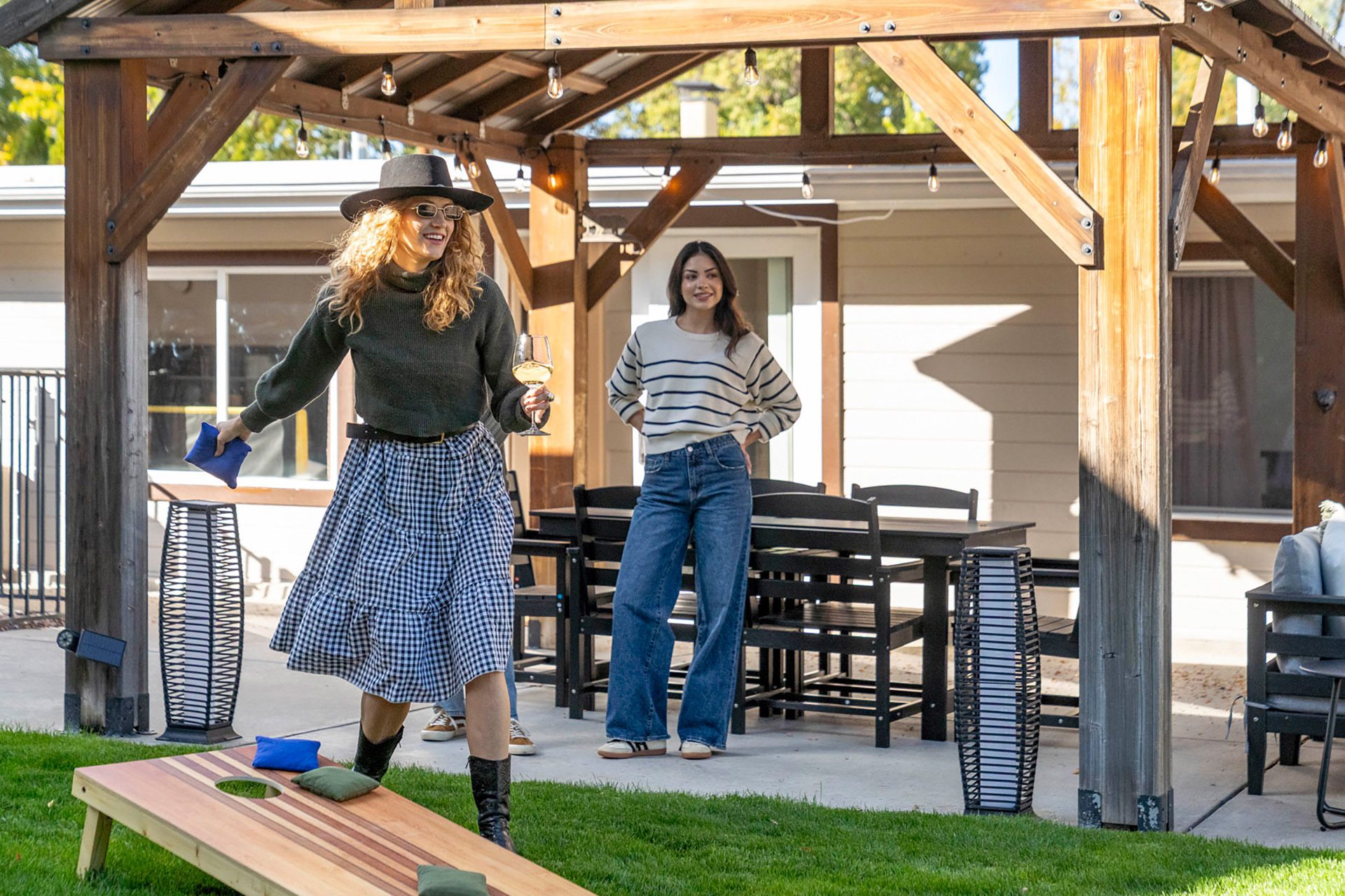 Guests enjoying cornhole under a pergola in Colorado short-term rental yard